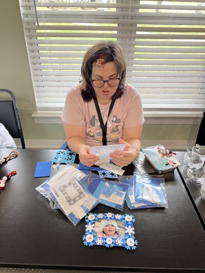 Women will supplies to make a foam picture frame with snowflake decorations
