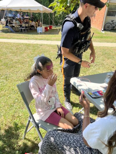 Kid with her face painted next to a police officer