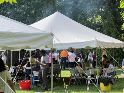 People sitting around two tables under a tent