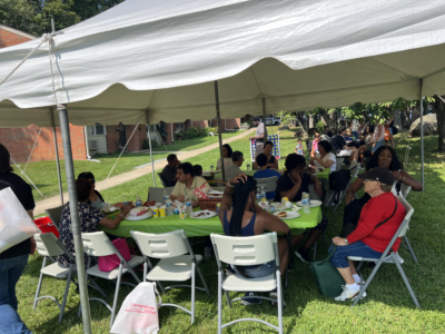 People sitting around two tables under a tent
