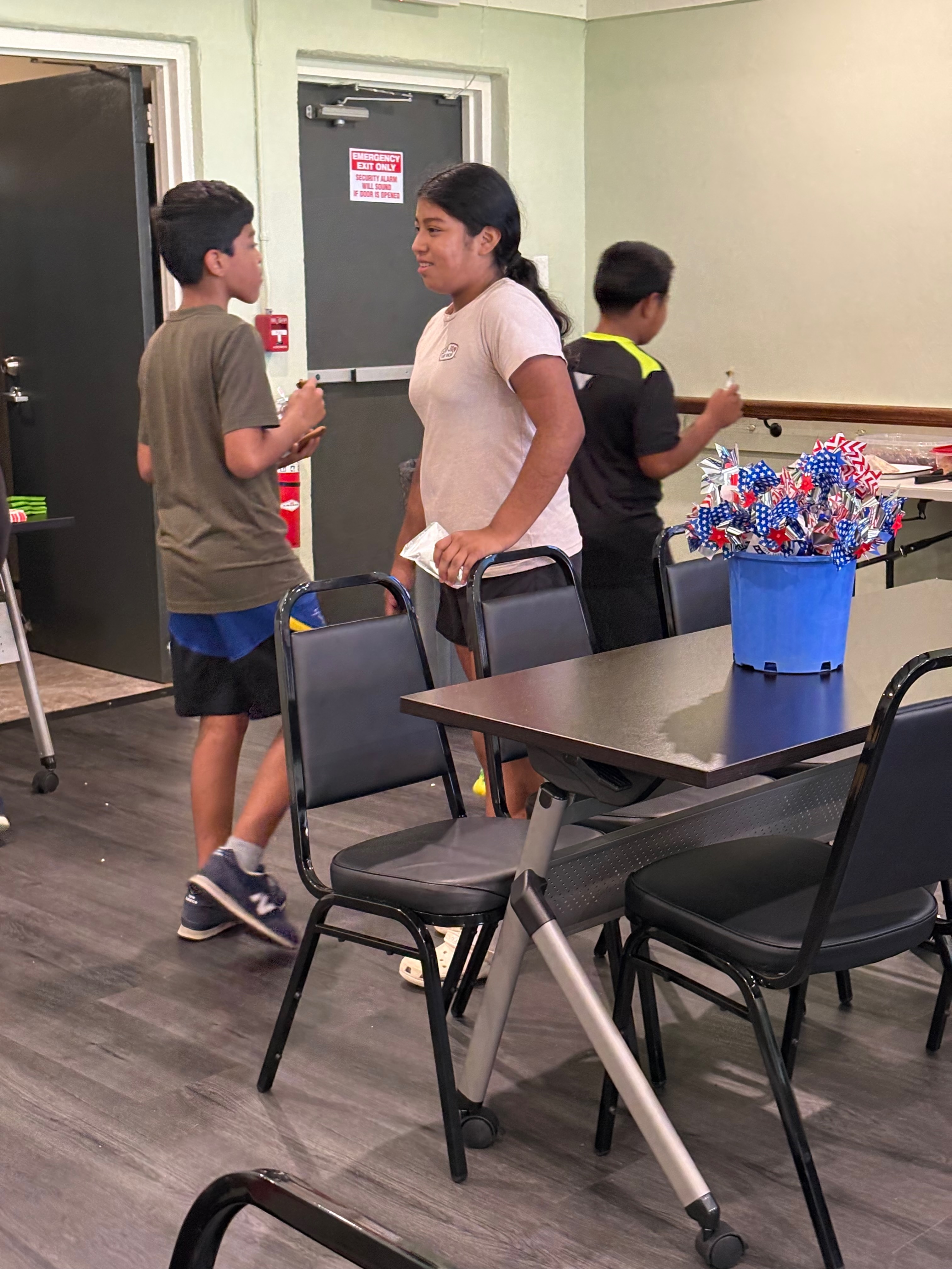 Children standing by a bucket of flags